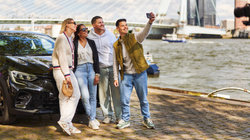 Jong volwassenen maken met de auto een selfie bij de Erasmusbrug.