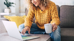 Vrouw achter de laptop op de bank