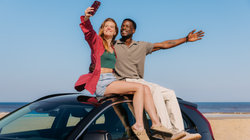 Couple sit on the car on the beach