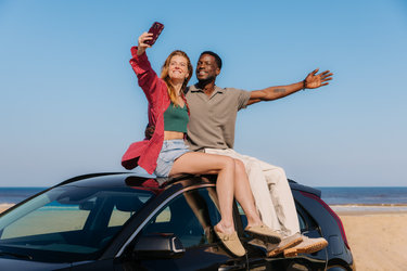 Koppel zit op de auto op het strand