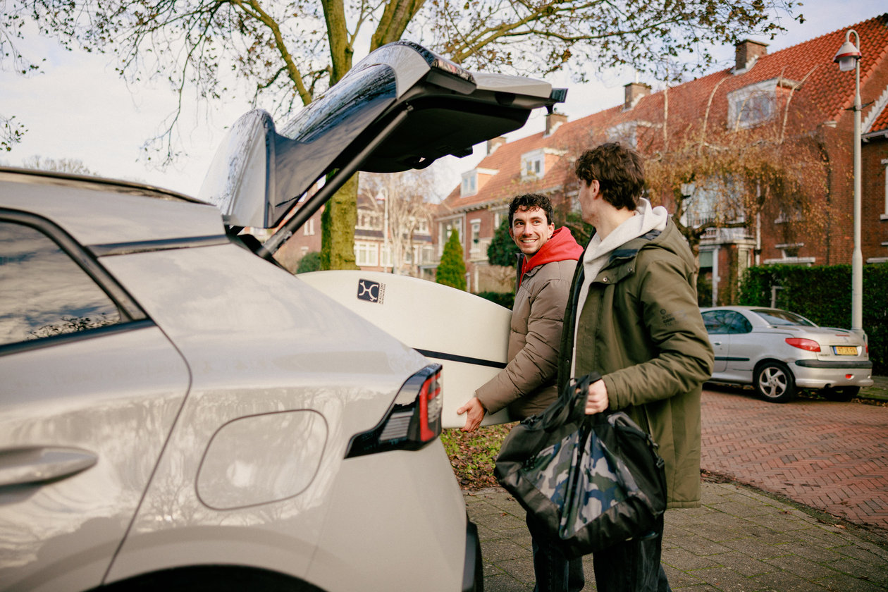 Two men pack surfing gear in the car