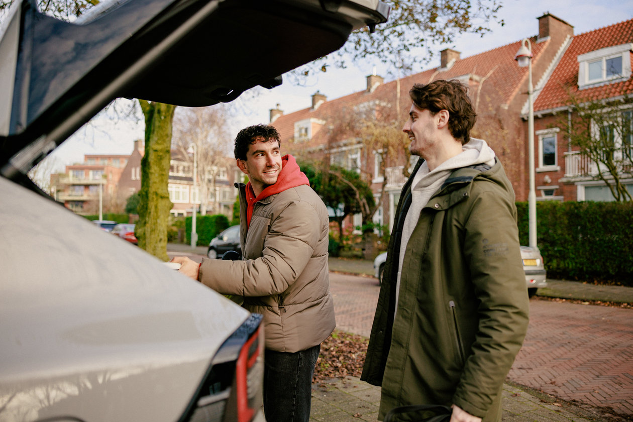 Two men pack surfing gear in the car