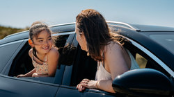Mother and daughter in the car on the beach