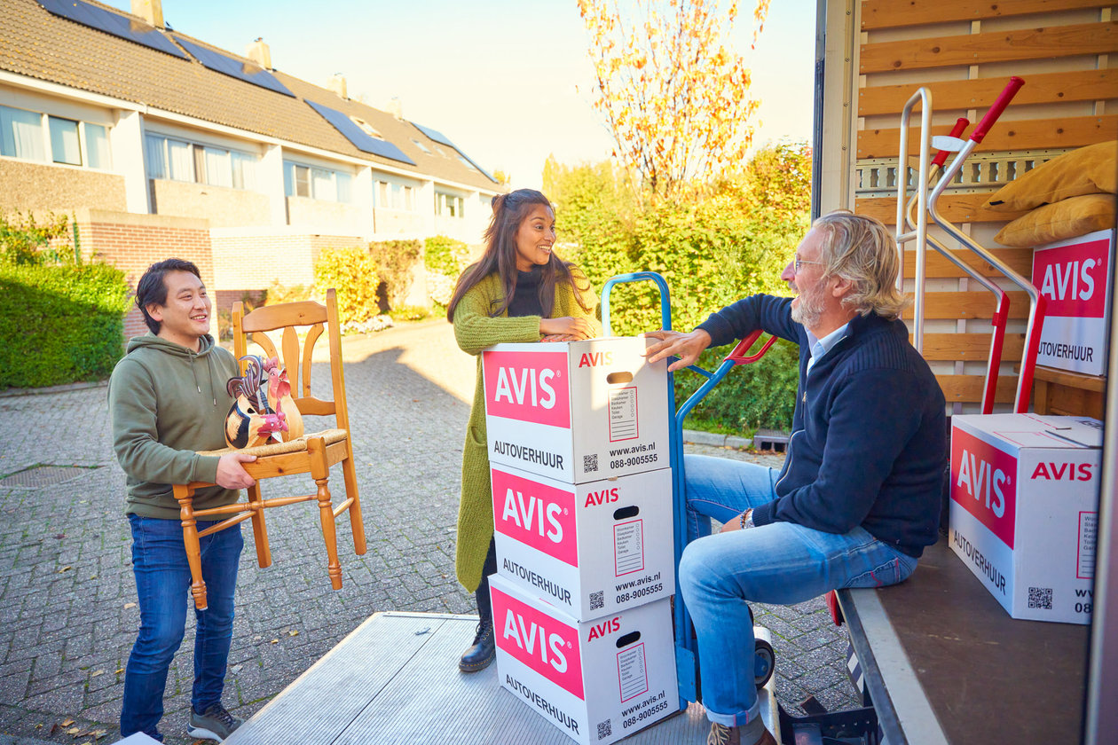 3 mensen staan op de laadklep van de verhuisbus met verhuis spullen