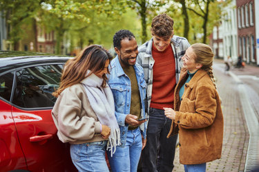 4 young adults hanging out by the car