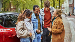 4 jongvolwassenen hangen bij de auto