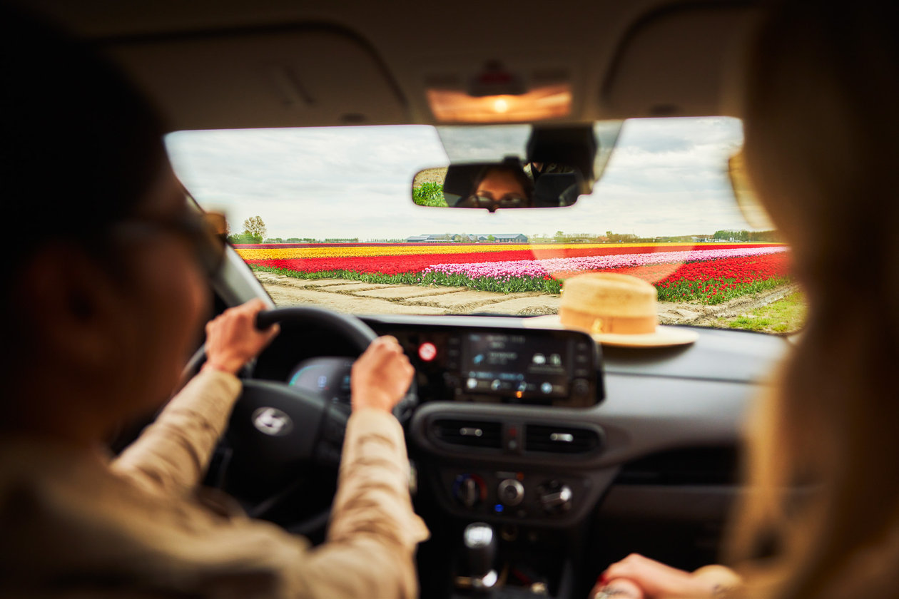 Twee vrouwen zitten voorin de auto bij een tulpenveld