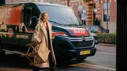 Woman walks past Avis van with a stool