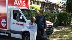 Vader en dochter staan voor de Avis bus